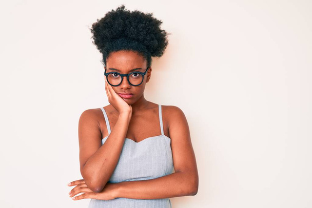 jonge afrikaanse amerikaanse vrouw dragen casual kleding en bril denken kijken moe en verveeld met depressie problemen met gekruiste armen.  - Foto, afbeelding