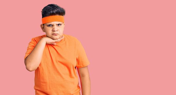 Kleine jongen draagt sportkleding die keel doorsnijdt met de hand als mes, bedreigen agressie met woedend geweld  - Foto, afbeelding