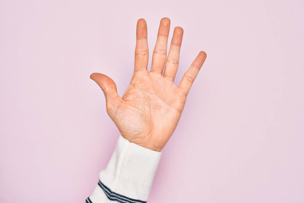 Mano de joven caucásico mostrando dedos sobre fondo rosa aislado contando número 5 mostrando cinco dedos - Foto, imagen