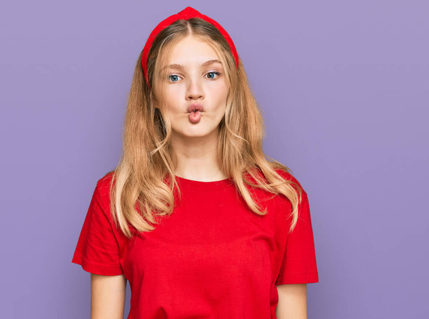Belle jeune fille caucasienne portant un t-shirt rouge décontracté faisant visage de poisson avec des lèvres, geste fou et comique. expression drôle.  - Photo, image