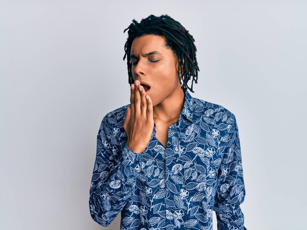 Junger afrikanisch-amerikanischer Mann in einem Hemd im 80er-Jahre-Stil gelangweilt gähnend müden Mund mit der Hand bedeckt. Ruhelos und schläfrig.  - Foto, Bild