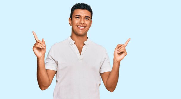 Jeune homme arabe portant des vêtements décontractés souriant confiant pointant avec les doigts vers différentes directions. espace de copie pour la publicité  - Photo, image