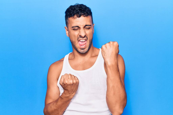 Young hispanic man wearing casual clothes celebrating surprised and amazed for success with arms raised and eyes closed  - Photo, Image
