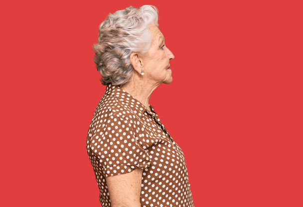 Senior grauhaarige Frau trägt lässige Kleidung mit Blick zur Seite, entspannen Profil Pose mit natürlichem Gesicht mit selbstbewusstem Lächeln.  - Foto, Bild