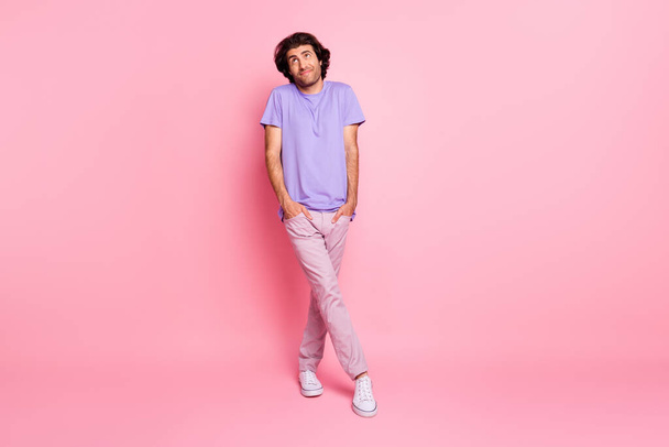Full length photo of shy man look up empty space wear violet t-shirt pants footwear isolated pastel pink color background - Fotoğraf, Görsel