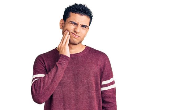 Hispanic handsome young man wearing casual clothes touching mouth with hand with painful expression because of toothache or dental illness on teeth. dentist  - Foto, Bild