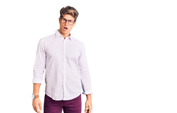 Young handsome man wearing business clothes and glasses in shock face, looking skeptical and sarcastic, surprised with open mouth  - Fotografie, Obrázek