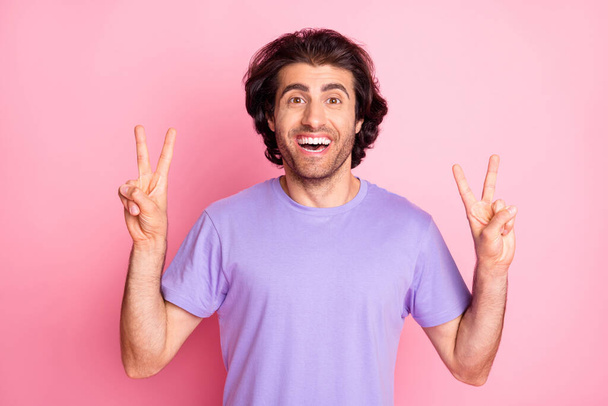 Photo of handsome guy two hands show v-sign open mouth wear purple t-shirt isolated pastel pink color background - Фото, зображення