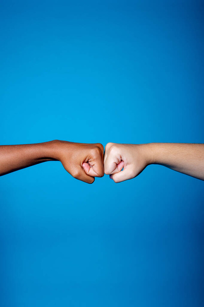 Manos de mujeres blancas y negras mostrando su amistad y respeto sobre fondo azul - Manos femeninas multiétnicas aisladas apoyando - hermandad, racismo, concepto de igualdad - Foto, imagen