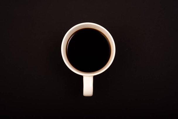 Top view of white ceramic mug with black coffee on black background. - Photo, Image