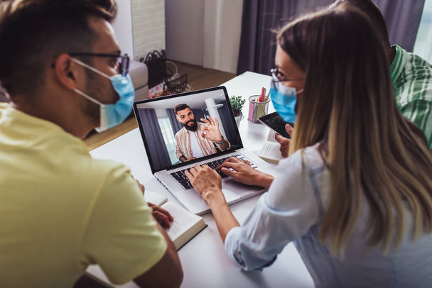 Three people men at working in the office wearing medical mask for protection by Coronavirus, Covid-19. Leader greets in a video call conference. - 写真・画像