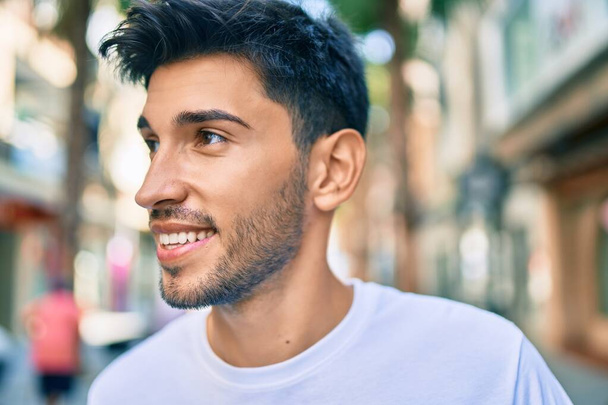 Fiatal latin férfi mosolyog boldog séta a városban. - Fotó, kép