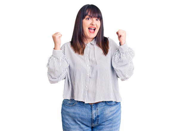 Young plus size woman wearing casual clothes celebrating surprised and amazed for success with arms raised and open eyes. winner concept.  - Foto, Bild