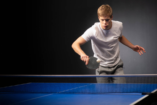 Portret młodego mężczyzny grającego w tenisa na czarnym tle - Zdjęcie, obraz