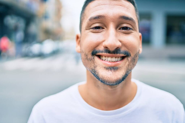 若いヒスパニック系の男が幸せな街の通りを歩いて笑っている. - 写真・画像