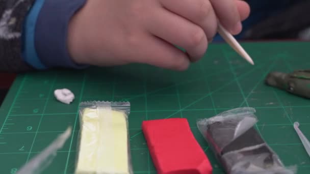 Movimiento panorámico de las manos de un joven moldeando una figura con pasta de modelado sobre una mesa de manualidades - Metraje, vídeo
