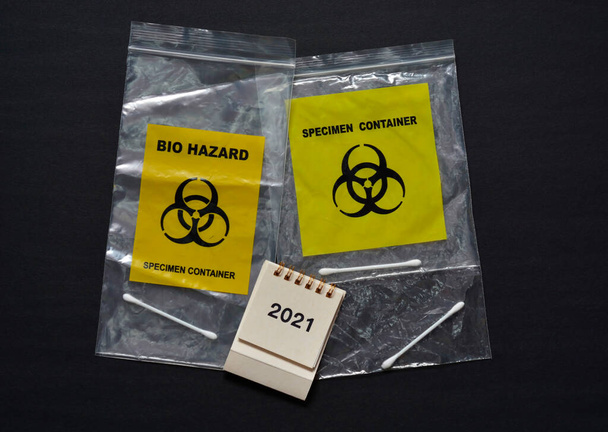 Bio Hazard Specimen Zip Lock Bag en witte kalender 2021 op donkere achtergrond. Concept gezondheidszorg - Foto, afbeelding
