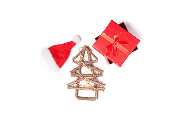 Wooden Christmas tree, xmas cap and red gift on white isolated background with copy space - Fotoğraf, Görsel