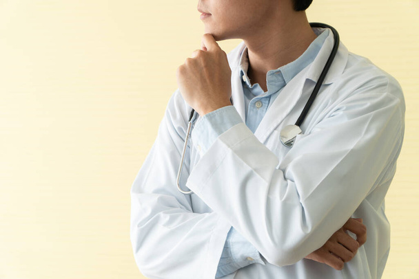 Retrato del joven médico asiático con los brazos cruzados sosteniendo estetoscopio en la vuelta de emergencia del hospital. Concepto de estilo de vida del paciente sanitario y médico. - Foto, Imagen