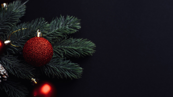 Christmas tree branch with red Christmas balls on a black background. Xmas greeting card with space. Flat lay, top view - Foto, imagen