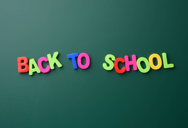 inscription back to school from multicolored plastic letters on green chalk board - Photo, image