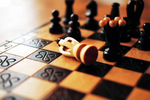 Figure of white king lying on the chessboard as a sign of resining - filtered closeup with selective focus - Photo, Image