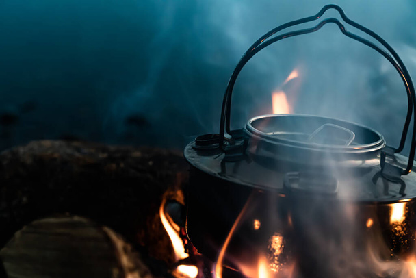 Ocelová konvice vařící vodu v plamenech táborového ohně. Zavřít. . Kvalitní fotografie - Fotografie, Obrázek