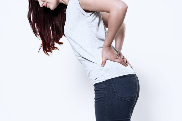 Girl holds hands on her sore back on white. - Foto, Imagen