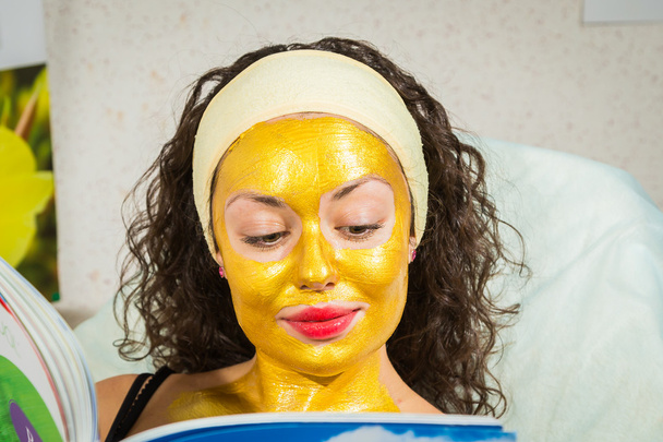kobieta w złota maska twarzy czytania magazynu - Zdjęcie, obraz
