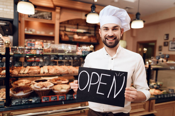 Young Happy Man with Open Sign Standing in Bakery. - Foto, Imagen
