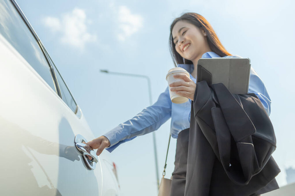 hand of  businesswoman hand hold cup of coffee and tablet and right hand  opening a car door. - Foto, imagen