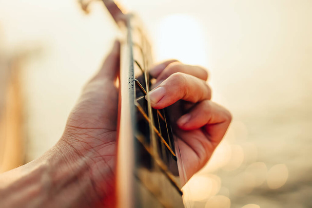 man playing guitar on sunset sea beach. - Фото, зображення