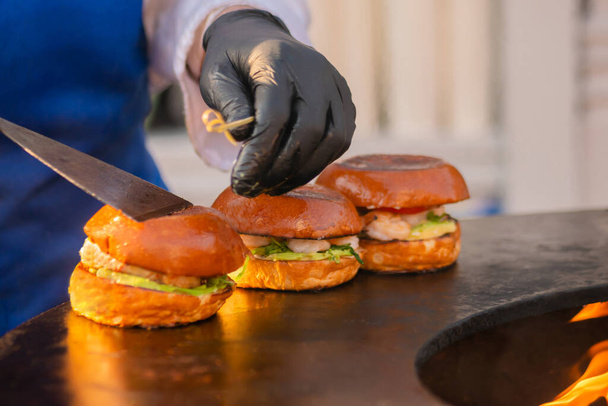 Szef kuchni przygotowuje hamburgery rybne na festiwalu ulicznego jedzenia na świeżym powietrzu - zbliżenie - Zdjęcie, obraz