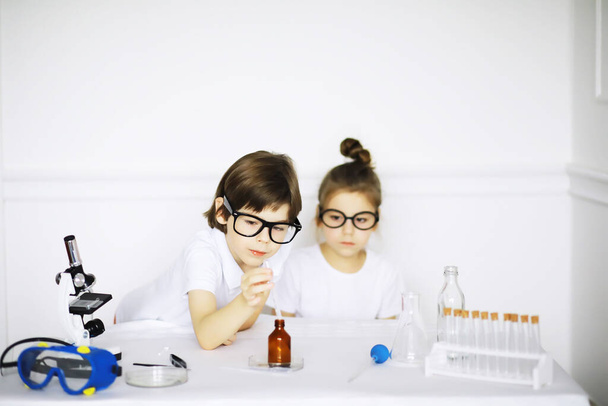 Kimya dersindeki iki tatlı çocuk beyaz arka grubunda deneyler yapıyor. - Fotoğraf, Görsel