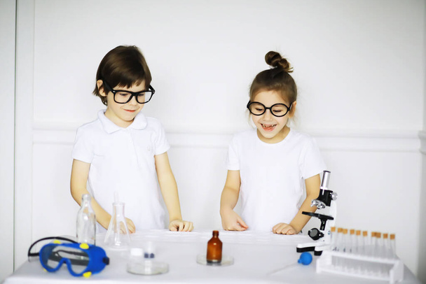 Dvě roztomilé děti na hodině chemie dělat experimenty izolované na bílém pozadí - Fotografie, Obrázek