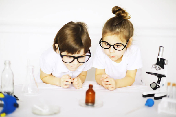 Δύο χαριτωμένα παιδιά στο μάθημα χημείας που κάνουν πειράματα απομονωμένα σε λευκό backgroun - Φωτογραφία, εικόνα