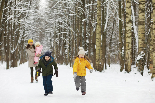 Счастливая семья играет и смеется зимой на улице в снегу. Зимний день в парке. - Фото, изображение