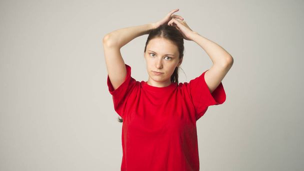 girl on a gray background holds hair in her hand, a problem with the hair - Photo, Image