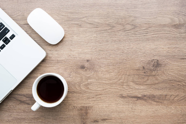 Drewniany minimalistyczny stół biurowy z laptopową filiżanką kawy i bezprzewodową myszą. Widok z góry z miejsca do kopiowania, płaski leżak. - Zdjęcie, obraz