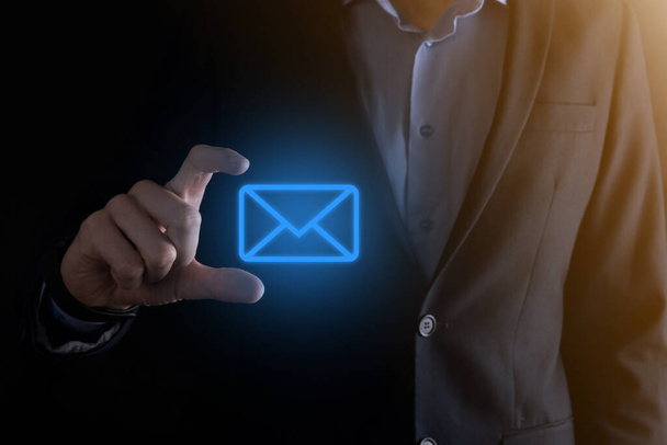 Businessman hand holding e-mail icon, Contact us by newsletter email and protect your personal information from spam mail. Customer service call center contact us concept. - Photo, Image