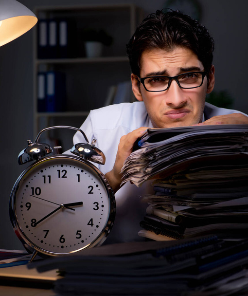 Jeune homme d'affaires travaillant des heures supplémentaires tard dans le bureau - Photo, image
