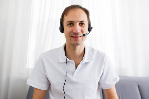 Portrait of happy mature man making hand gestures while conversing with a video call at laptop with earphones. Cheerful casual businessman doing video calling at home. - Photo, Image