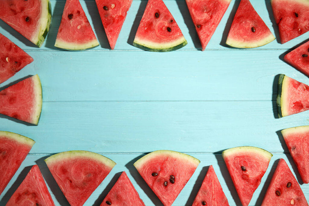 Frame made with slices of ripe watermelon on light blue wooden table, flat lay. Space for text - Valokuva, kuva