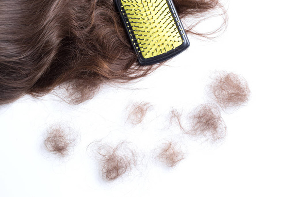 Haarbürste auf einem Haar und unbeholfenes Haar auf weißem Hintergrund. - Foto, Bild