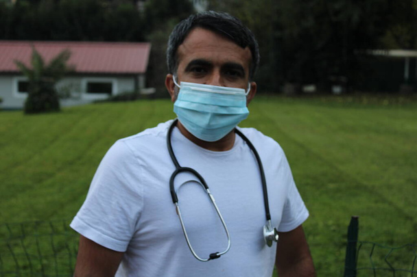 médico varón con estetoscopio y mascarilla al aire libre - Foto, Imagen