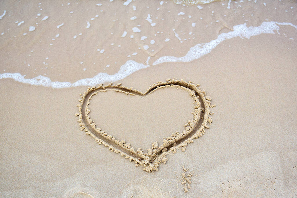 Fingergezeichnetes Herz auf nassem Sand am Strand. Romantischer Ausflug ans Meer. Zeichen der Liebe. - Foto, Bild