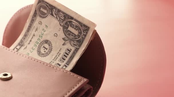 Dinero en efectivo en dólares en una pequeña billetera sobre fondo rosa  - Metraje, vídeo