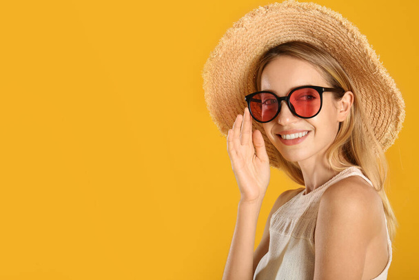 Beautiful woman in stylish sunglasses on yellow background. Space for text - Foto, Imagem