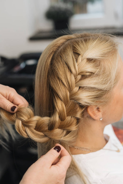 девушка в парикмахерской, стилист делают прическу для клиента в женских волосах в парикмахерской, близкий вид рук, шип  - Фото, изображение