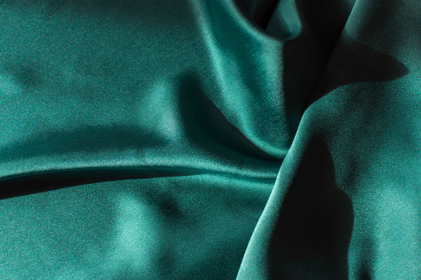 Zelená saténová tkanina balí zblízka. Abstraktní trend pozadí 2021 Tidewater zelená barva.Luxusní elegantní světlé textury s tvrdým světlem s copyspace.Banner design na Vánoce, Valentýna - Fotografie, Obrázek